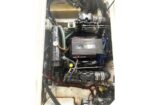 Mercury/MerCruiser boat engine in its engine bay, with hoses, wiring, and a black control module visible