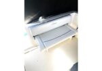 White Canon wide-format printer with its output/paper tray extended on a light floor.