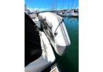 Inflatable dinghy strapped alongside a larger boat at a sunny marina with sailboats in the background