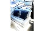 White boat cockpit seating with two dark blue starry throw pillows, sunlight on deck.