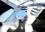 White boat cockpit lounge with L-shaped cushions, striped pillows, and a round cup-holder table.