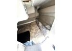Narrow sleeping berth with a mattress, blanket, and a pillow tucked against angled walls in a small cabin interior