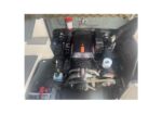 Boat engine compartment showing a compact diesel engine with belts, hoses, and a battery on the lower left.