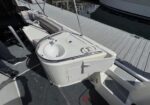 Built-in boat galley sink with faucet and prep area on a deck, marina in the background