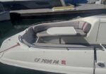White motorboat stern with U-shaped seating and a small central table, docked at a marina; registration CF 7696 PA visible.