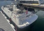 White motorboat docked at a marina, US flag at the stern and the name MICDI visible on the back.