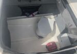 Inside a small boat cockpit: a white bucket in the center, a red portable fuel tank in the corner, a gray storage box, and a mesh net on the aft wall.