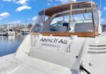Rear of a white luxury motor yacht named 'Above It All', Redondo Beach, CA, moored in a marina under a bright blue sky.