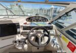 Boat cockpit helm with steering wheel, gauges, throttle levers, and navigation display.