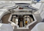 Open hatch reveals two inboard boat engines side by side in the engine bay, with a yellow dipstick visible.