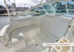 White boat cockpit with curved, clean bench seating and glossy deck; marina visible outside; upholstery in good condition.