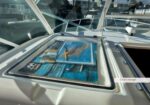 Open hatch on a boat showing folded marine charts in a chart storage area at a marina.