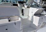 White yacht cockpit with built-in storage, coolers, and seating on a sunlit deck.