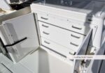 White metal cabinet with five drawers and an open side door, labeled 'Locking Tackle Station' on a boat or marine setup.