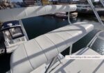 White cushioned upper-deck seating on a yacht with a marina and water in the background.