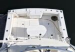 Top-down view of a white boat cockpit from above, showing a central helm seat, deck seating, and a coiled rope on the right.