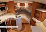 Cozy boat cabin with a U-shaped lounge, compact kitchen, and wooden cabinetry; there’s a caption reading “Incredibly well appointed cabin!”.