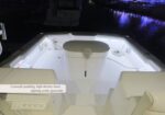 White boat cockpit at night with seating along the sides; a label on gunwale padding mentions high-density foam and lighting under the gunwales.
