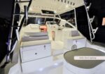 White luxury yacht deck at night with seating benches, storage boxes, and the helm station; deck lighting label visible.