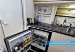 Compact boat galley with open fridge, microwave, sink, and neatly arranged supplies for easy access while cooking.