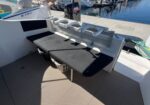 Rear deck seating on a docked boat with a black cushion and metal rails, marina background