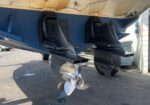 Twin outboard motors attached to the stern of a boat, with exposed lower units and three-blade propellers.