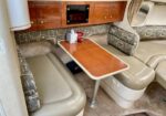 RV dinette table with cushioned bench seating and wood cabinets overhead, compact dining area in a trailer interior