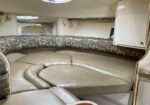 Curved beige leather seating area in a small boat cabin, with patterned back cushions and a circular center section.
