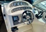 Boat cockpit helm with steering wheel, multiple gauges, and navigation electronics visible on the dashboard.