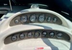 Close-up of a boat's instrument panel with two rows of round gauges mounted on a carbon-fiber-like dashboard.