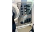 Close-up of a metal control panel with multiple black toggle switches and a large round dial on the left side.
