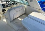 White motorboat cockpit with a plush captain chair, steering wheel, and instrument panel; a fold-down table is in front.