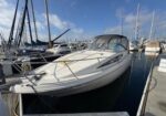 White motorboat moored at a marina with other boats and blue sky above.