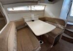 U-shaped beige seating area around a small white table in a boat cabin; a paper towel roll sits on the table.