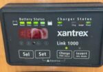 Black Xantrex Link 1000 battery/charger controller with red LED display showing 4.00, labeled status lights and buttons (Sel/Set, Charge, Invert)