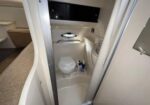 Compact boat bathroom (marine head) featuring a small toilet, sink, and curved walls in a tight cabin area