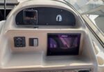 Boat helm with navigation gear: a Simrad display screen and control panel on a beige console.