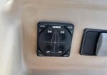 Lenco trim-tab control panel on a beige boat dashboard, featuring a four-way joystick with UP and DN indicators.