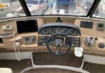 Boat cockpit helm with steering wheel, multiple gauges, and navigation screens facing forward at the helm station far above the cabin floor.