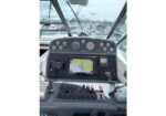 Boat helm with GPS/chart display and throttles, facing a marina through the windows
