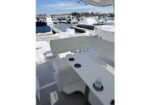 White yacht deck with a built‑in table and cup holders, overlooking a marina full of moored boats on a sunny day.
