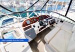 Boat cockpit with wooden dashboard, steering wheel, and white leather seating; caption says 'Great visibility from the Helm'.