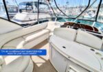 White leather seating and helm in a boat cockpit with marina views; flybridge offers air-conditioned and heated year-round comfort.