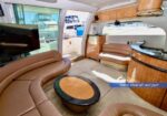 Luxurious yacht salon with tan leather seating around a round coffee table and wood cabinetry.