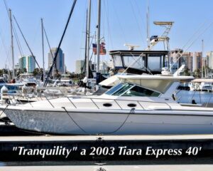 2003-tiara-4000-express-power-9929415-20250830142517147-1 | Boat Universe White Tiara Express 40 motor yacht named 'Tranquility' docked at a marina with a city skyline in the background.