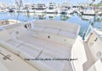 White yacht cockpit with plush seating and open space for entertaining, moored at a marina.
