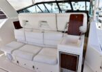 White cushioned seating area on a yacht cockpit with a small sink and compact fridge nearby.