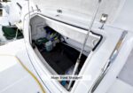 Open sailboat hatch revealing a roomy trunk storage with life jackets, hoses, and gear inside