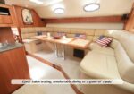 U-shaped beige sofa seating around a wood table in a yacht salon, with American flag pillows and warm wood paneling