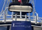 Rear of a yacht deck seen from below, with metal railings and a blue sign reading 'Offered by Shoreline Yacht Group'.